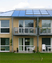Rønnebækhave bebyggelsen: facade med vinduer og tag med solfangere og -celler